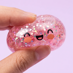Brokatowa kulka squishy ze uśmiechniętą buzią w dłoni